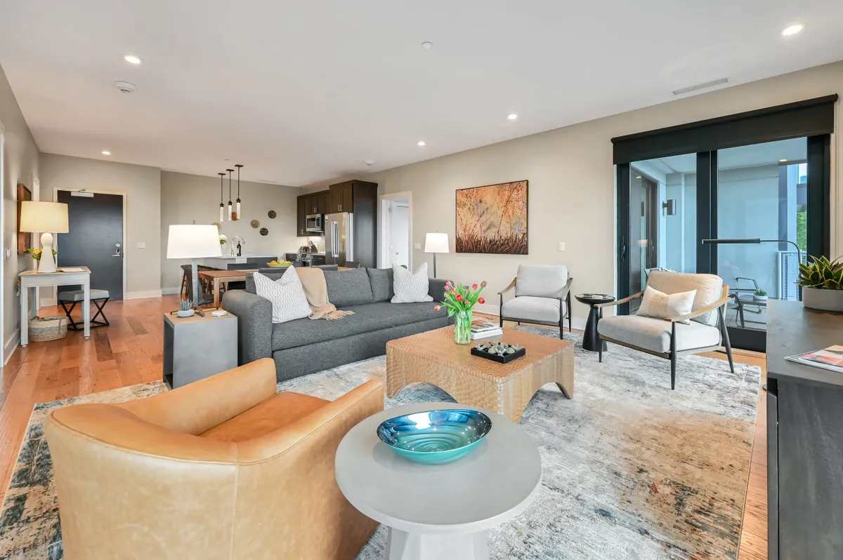 A welcoming living area featuring comfortable seating, a stylish coffee table, and sliding glass doors that lead to an outdoor space. The scene is set for socializing, hosting gatherings, or simply relaxing with friends after an energetic evening out. The visible outdoor connection hints at the urban environment and the possibility of indoor-outdoor living.