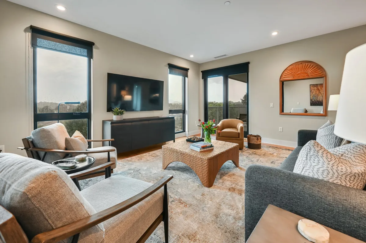 This interior image features a comfortable living space with armchairs, a coffee table, a decorative mirror, and large windows that offer scenic views. The layout is open and welcoming, suggesting a well-managed and inviting environment ideal for both privacy and socializing after check-in. The windows connect the interior to the outside world, reinforcing the sense of convenience and accessibility mentioned in the section.